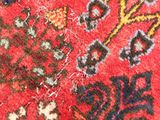 a close up of a red rug with a bird on it