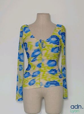 haut à manches longues orné de fleurs bleues et jaunes, présenté sur un torse de mannequin