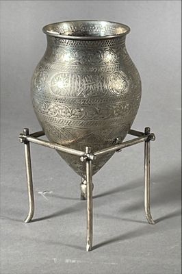 un vase en argent posé sur un socle, sur un fond gris