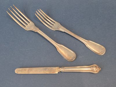 three forks and a knife on a table with a blue background