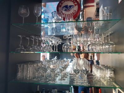 a glass shelf with wine glasses and a clock on it