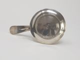 a silver cup with a spoon in it on a white surface
