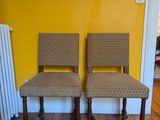 une paire de fauteuils rembourrés devant un tableau, dans une pièce jaune