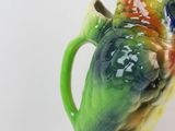 a green and orange bird sitting on top of a green cup