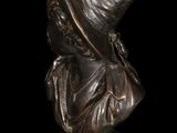 bronze bust of a woman with a hat on a black background
