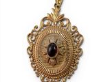 an image of a gold pendant with a garnet stone in the center