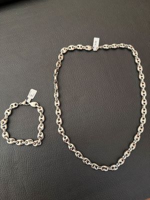 a close up of a silver chain necklace and bracelet on a table
