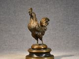 bronze statue of a rooster on a pedestal on a gray background