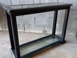 une vitrine en verre noir posée sur un sol en ciment