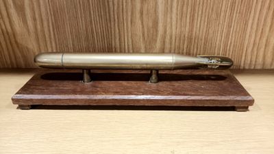 un stylo en argent posé sur un support en bois, sur une table