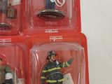 four firemen figurines in plastic packaging on a white surface