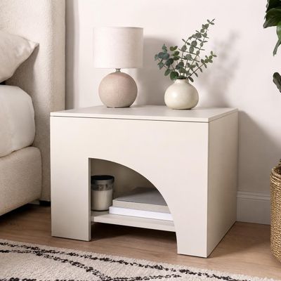 une table blanche sur laquelle est posée une lampe, à côté d'un lit