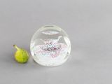 une petite figurine en verre posée à côté d'une autre figurine sur une table