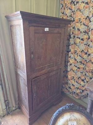 a wooden cabinet in a room with a flowered wallpaper