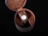 a watch in a leather case on a black surface