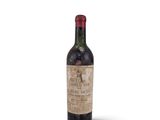 an old bottle of wine sitting on top of a white surface
