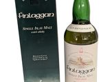 a bottle of whisky sitting next to a box on a white surface