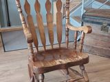 a wooden rocking chair sitting on a hard wood floor