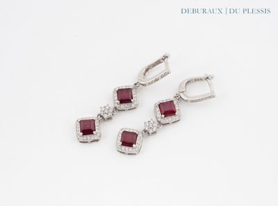 trois paires de boucles d'oreilles en rubis et diamants posées sur un fond blanc