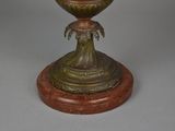 a bronze vase with a bird on top of it