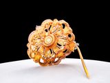 a gold brooch on a white plate with a black background