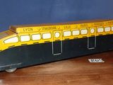 un petit bus jouet jaune et noir posé sur une table en bois