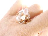 a woman ' s hand holding a ring with pearls and diamonds