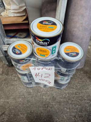 Plusieurs pots de peinture sont empilés les uns sur les autres devant un miroir