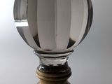 une boule de verre posée sur un socle en bois, sur fond blanc