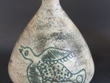 un petit vase avec un oiseau sur une table