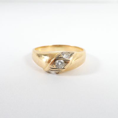 gros plan d'une bague en or et diamants sur une surface blanche