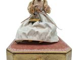 une figurine représentant une femme assise sur une boîte