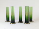 trois vases en verre vert posés les uns à côté des autres sur une surface blanche