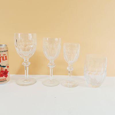 several empty wine glasses and a can of beer sit on a table