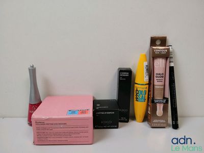 une boîte de mascara, une brosse à mascara, des eye-liners et d'autres produits de maquillage posés sur une table