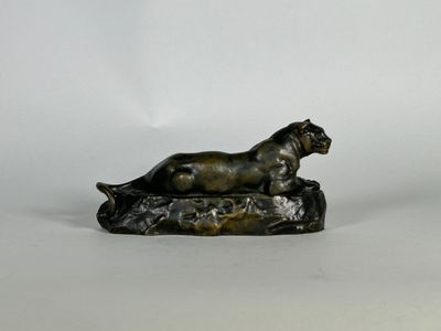 statue en bronze représentant un chien allongé sur un rocher, sur fond blanc