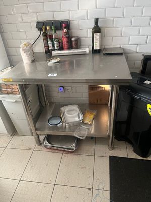 une cuisine équipée d'une table en inox et d'une poubelle noire