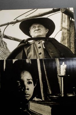 a black and white photo of a man in a cape and a woman in a hat