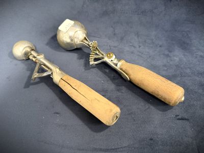 two silver spoons and a wooden spoon on a table