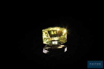 un diamant jaune dans l'obscurité, dont le reflet se dessine sur le sol