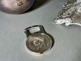 a silver bottle opener next to a silver ornament on a table