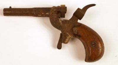 un vieux pistolet avec une poignée en bois sur une surface blanche