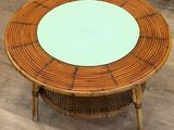 une table ronde avec un plateau en verre posée sur un parquet