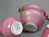 three pink teapots sitting on a table next to a white plate