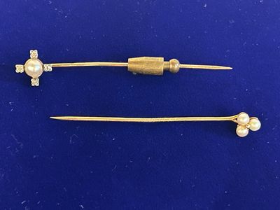 a pair of gold - plated hair pins with pearls on them
