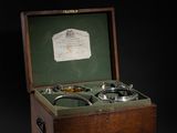 an old wooden box with two glasses in it on a black background