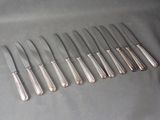 six silverplated knives are lined up in a row on a table