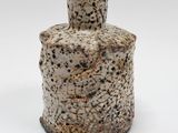 un petit vase posé sur une surface blanche