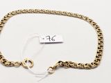 gros plan d'un bracelet en chaîne en or sur une surface blanche
