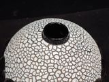 a white and black vase sitting on a black surface